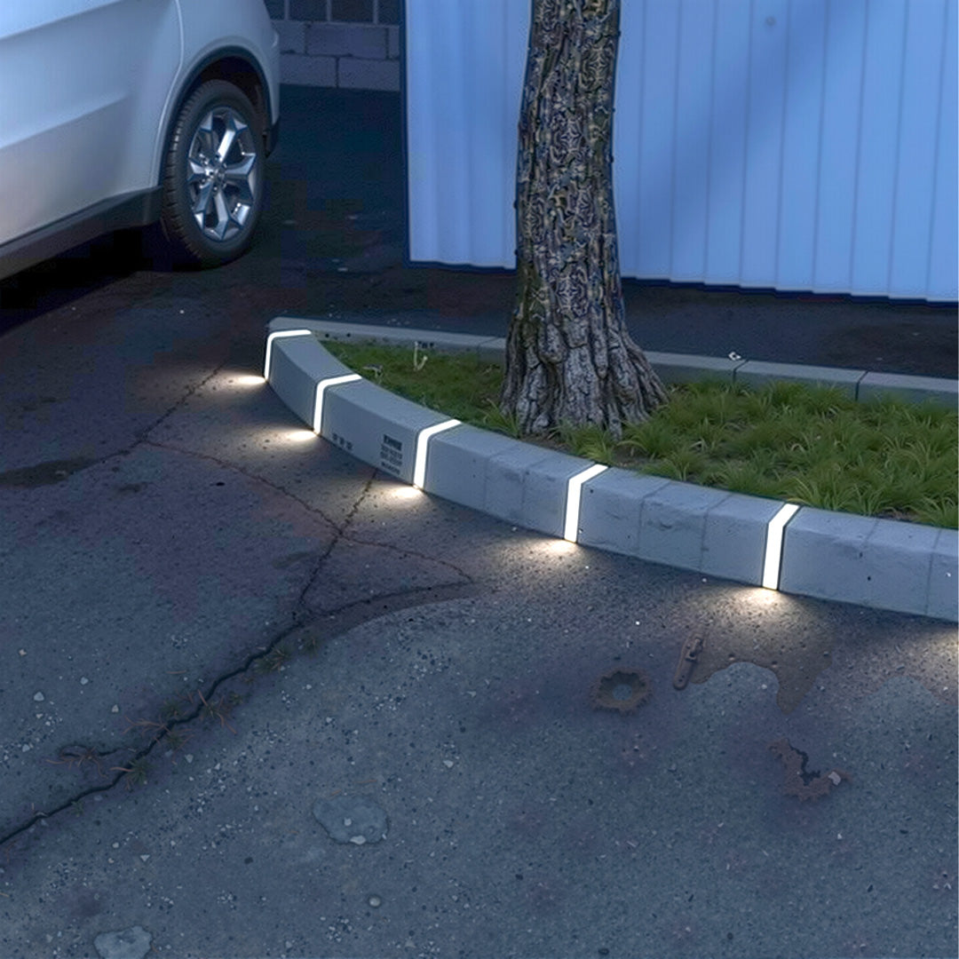 Deck lighting for steps installed along curved driveway curb creating continuous guiding light at night