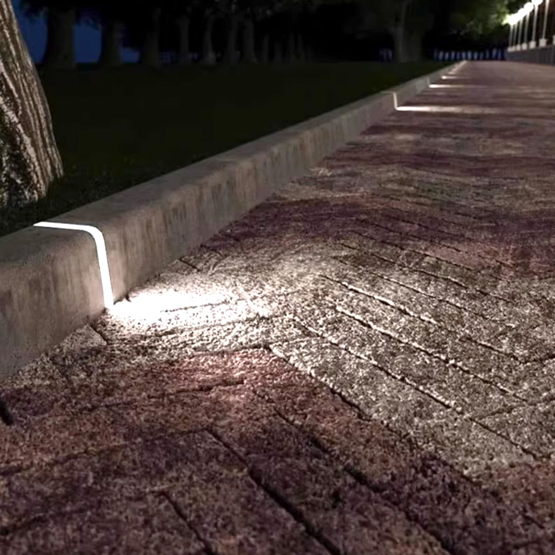 Deck lighting for steps mounted on raised garden border illuminating wooden pathway surface with warm downlighting