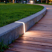 Deck lighting for steps integrated into stone border beside wooden walkway providing elegant pathway illumination