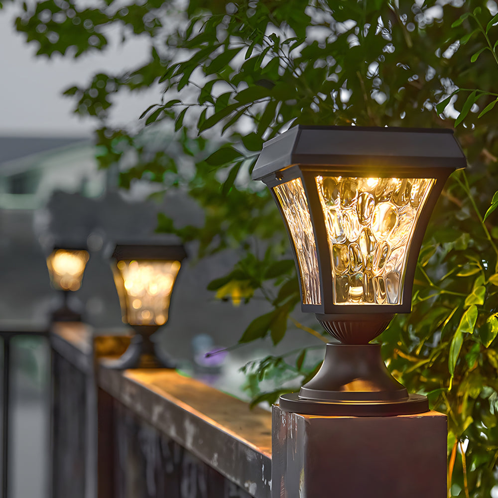 Warm LED post lights illuminating wooden deck railing with garden foliage in background during evening