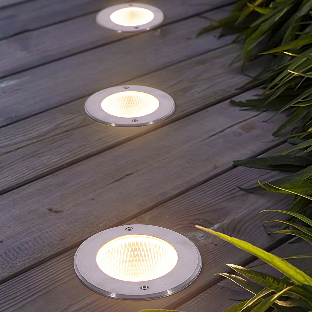 Linear arrangement of inground light fixtures embedded in wooden decking for modern outdoor lighting.