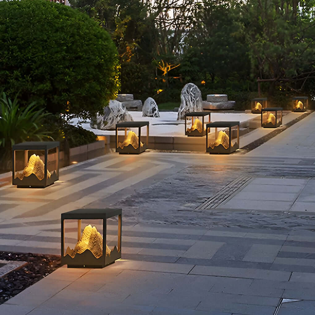 Decorate pillar light providing warm light along a minimalist garden walkway.