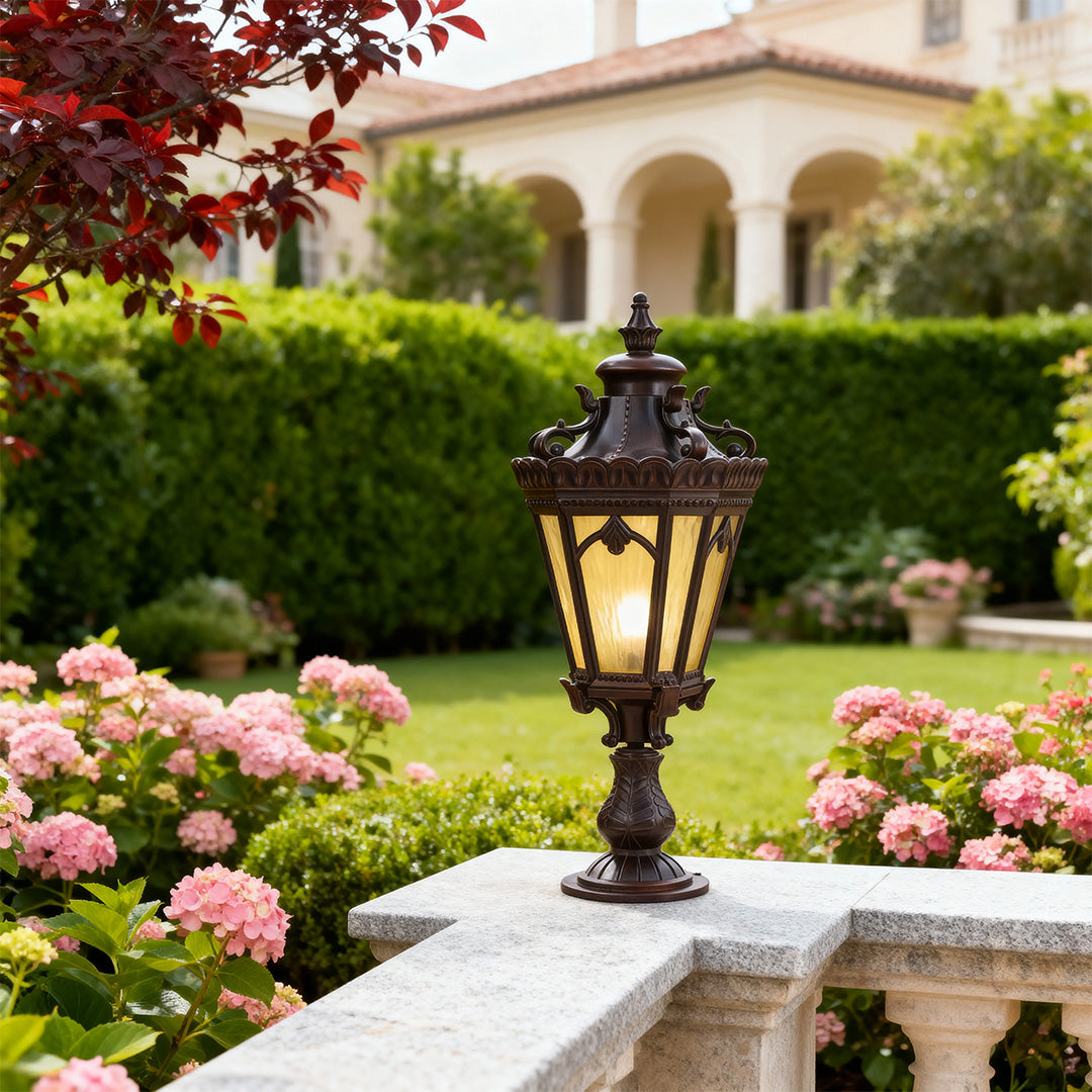 Decorative black outdoor pillar light illuminating garden pathway with pink roses and landscaped lawn