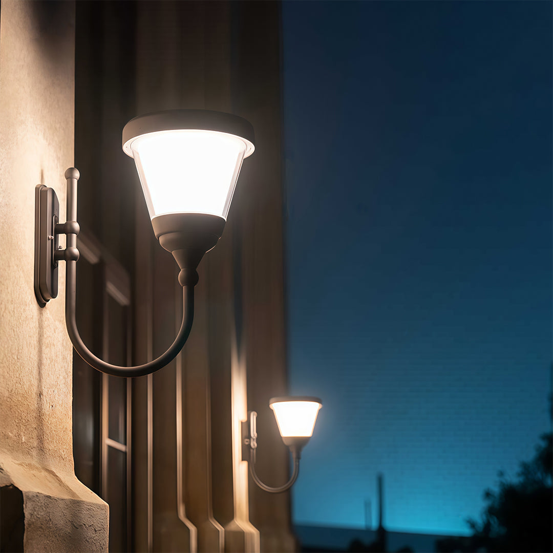 Decorative black outdoor wall light mounted along a brick wall, creating a cozy outdoor setting.