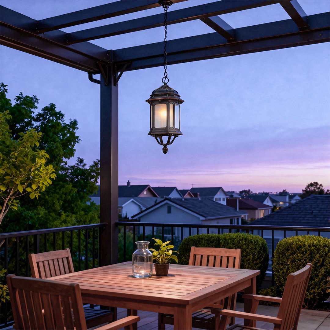 Decorative bollard LED light hanging from pergola over outdoor deck at twilight with pink sky