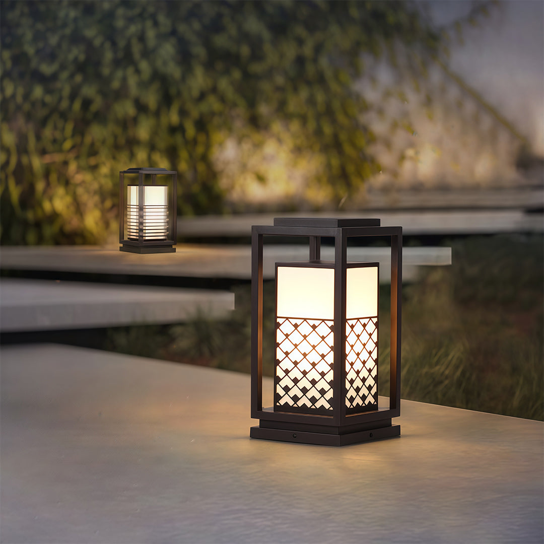 Decorative bollard light fixture with a lattice design, illuminating a beautifully landscaped outdoor space.
