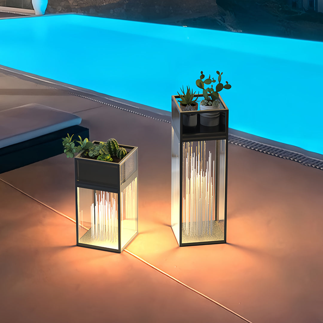 Decorative bollards with lights installed around a glowing blue pool in a nighttime outdoor scene.