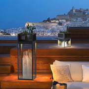 Decorative bollards with lights placed along a resort-style terrace overlooking the sea at dusk.