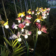 Decorative butterfly LED string lights with purple and yellow blooms in dark garden setting