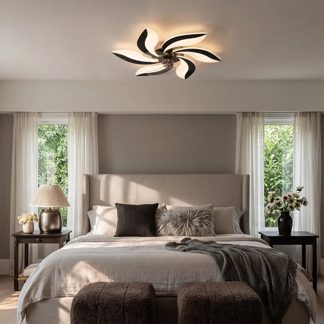 Decorative ceiling fans with lights installed above a gray bedroom with layered bedding and soft curtains.