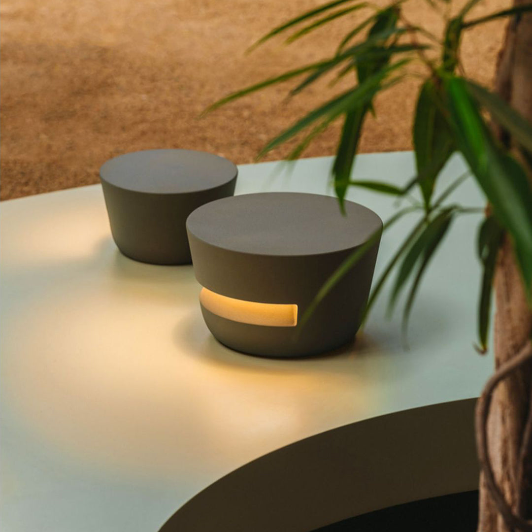 Decorative cylindrical black pathway lights placed on a light-colored outdoor side table, doubling as ambient patio lighting.