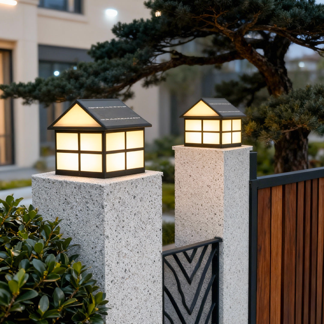 Decorative gate pillar top lights installed on textured stone pillars, illuminating the garden entrance warmly.