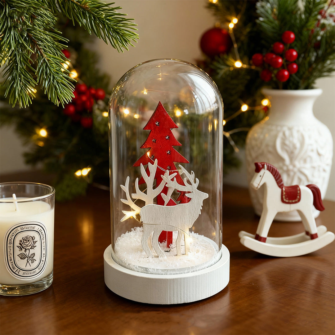 Decorative led table lamp with red festive scene under glass dome surrounded by holiday ornaments and greenery