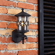 Decorative outdoor black sconce brightening red brick facade beside modern black window shutters