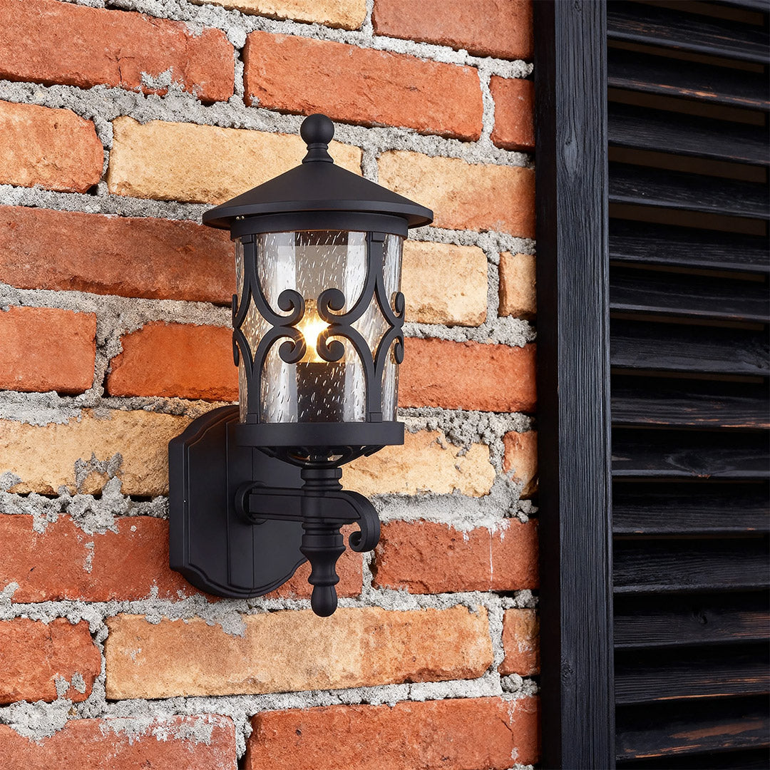 Decorative outdoor black sconce brightening red brick facade beside modern black window shutters