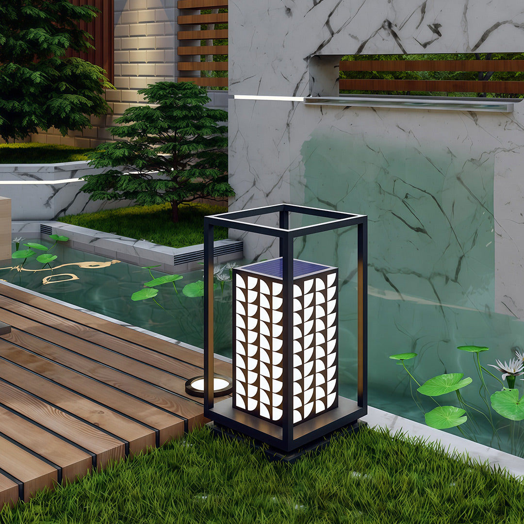 LED bollard light with detailed leaf pattern placed along a decorative outdoor path.