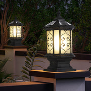 Decorative post cap lantern with intricate pattern design illuminating garden pathway at night