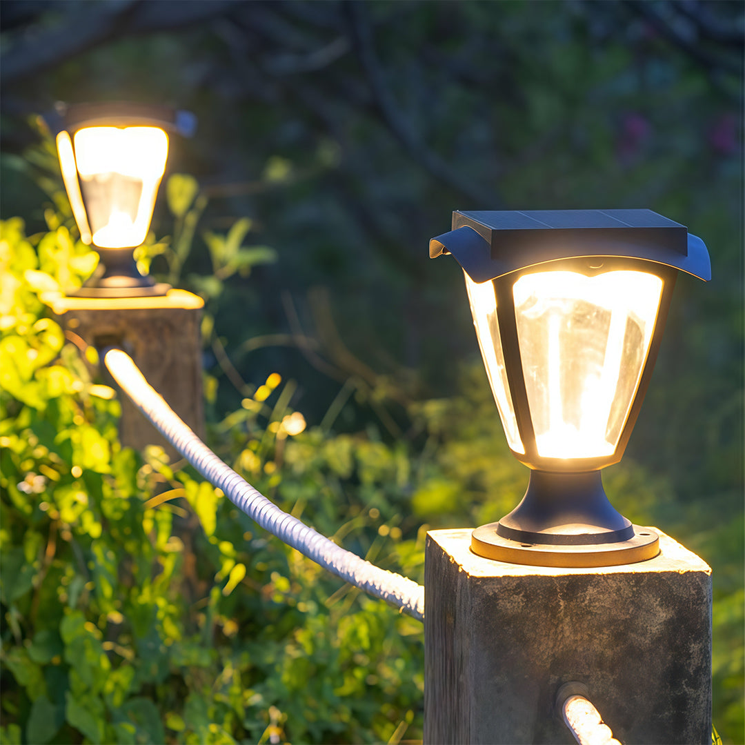Close-up of a decorative solar light pillar casting a warm, ambient glow on a garden post.