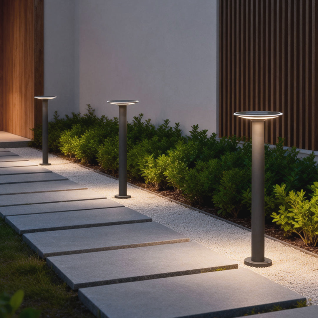 Decorative solar path lights illuminating a modern garden walkway with stone pavers, creating soft guiding light along the path.