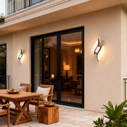 Designer black outdoor wall sconces with glass shade chandelier aesthetic providing architectural accent lighting on contemporary patio.