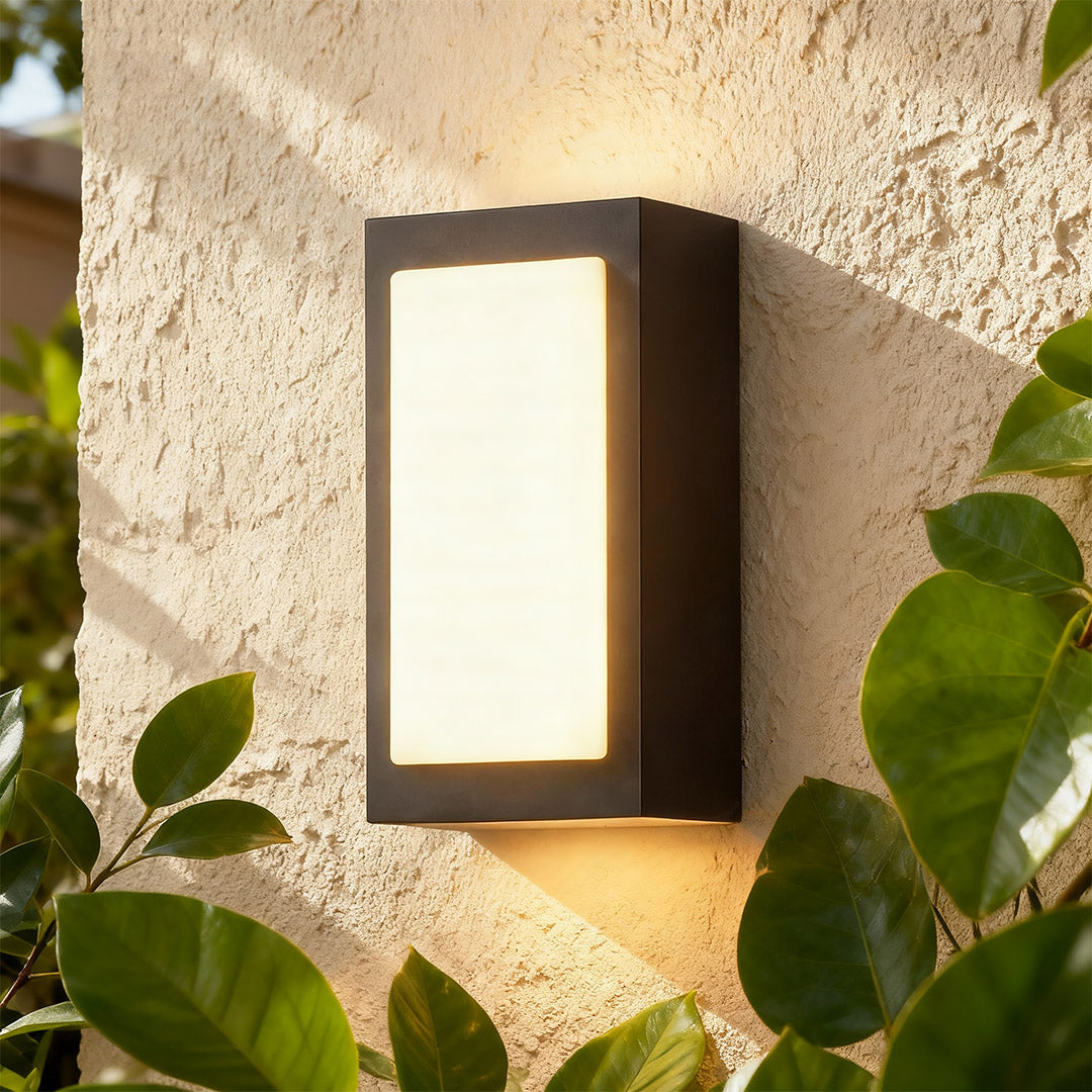 Designer black sconce wall lights with glass shade chandelier aesthetic creating beautiful ambient lighting on rough stucco exterior.