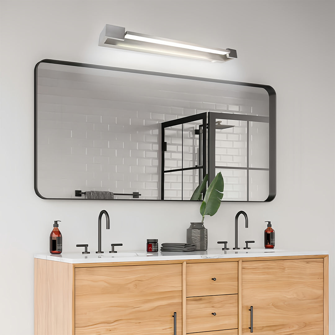 Designer chrome bathroom vanity light installed in modern bathroom above wooden vanity cabinet