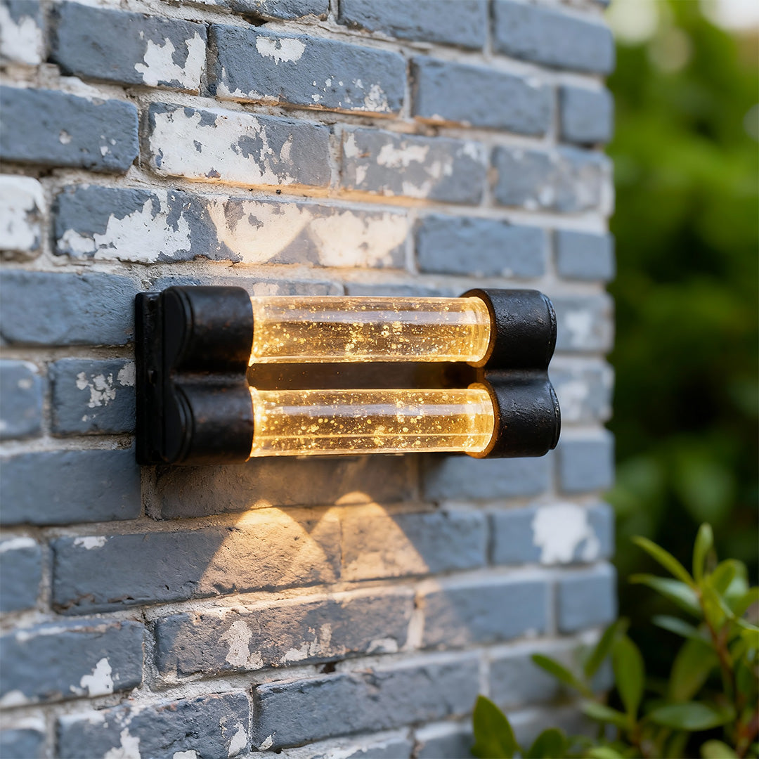 Designer crystal wall sconce light fixture with glass shade chandelier aesthetic on modern stone facade creating beautiful light patterns.