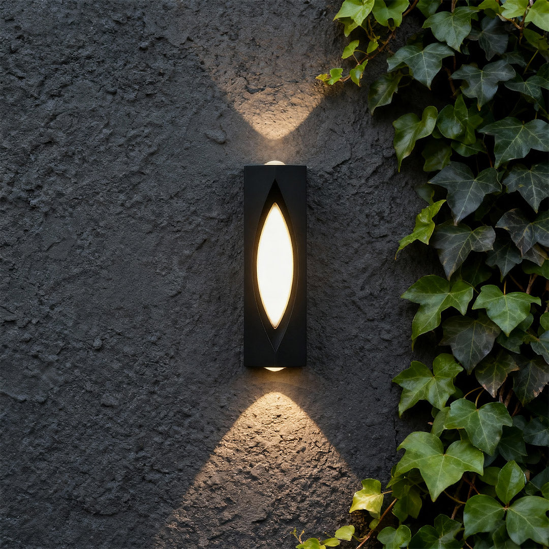 Designer decorative wall sconce lighting with glass shade chandelier aesthetic creating beautiful ambient glow on dark textured facade.