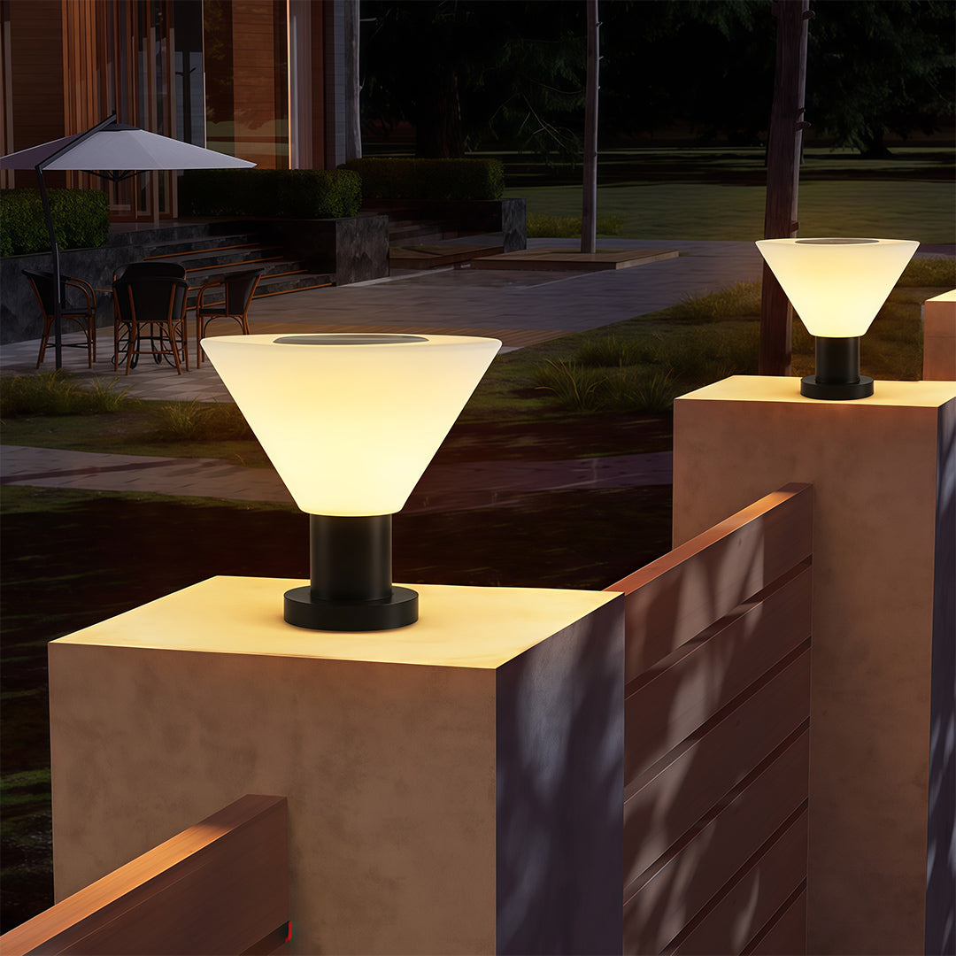Designer landscape pillar lighting featuring glass shade chandelier aesthetic creating warm welcoming glow on entrance pillars at dusk.