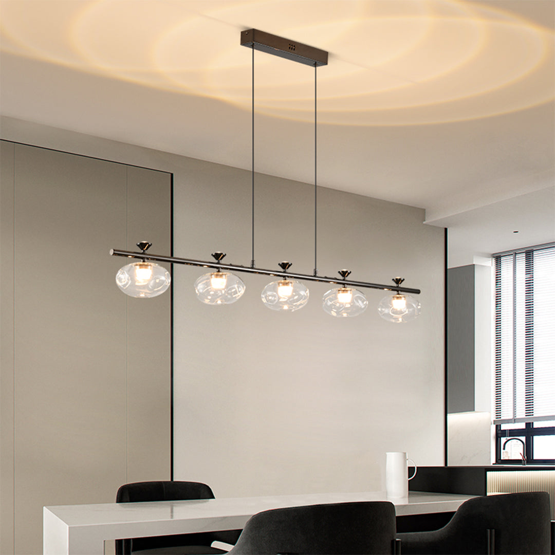 Designer linear glass chandelier installation over modern kitchen island with clear glass globes