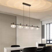 Designer linear glass chandelier installation over modern kitchen island with clear glass globes