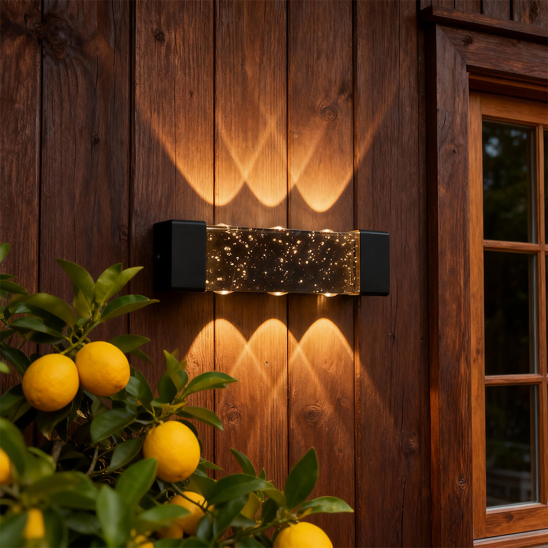 Designer up down wall light with glass shade chandelier aesthetic creating beautiful ambient glow on rustic wood exterior.
