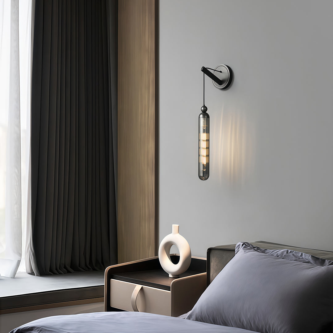 Designer wall mount pendant light featuring glass shade chandelier aesthetic providing task lighting beside modern bed.