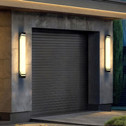 Designer wall mounted exterior lights with glass shade chandelier styling illuminating modern garage door entrance at dusk.