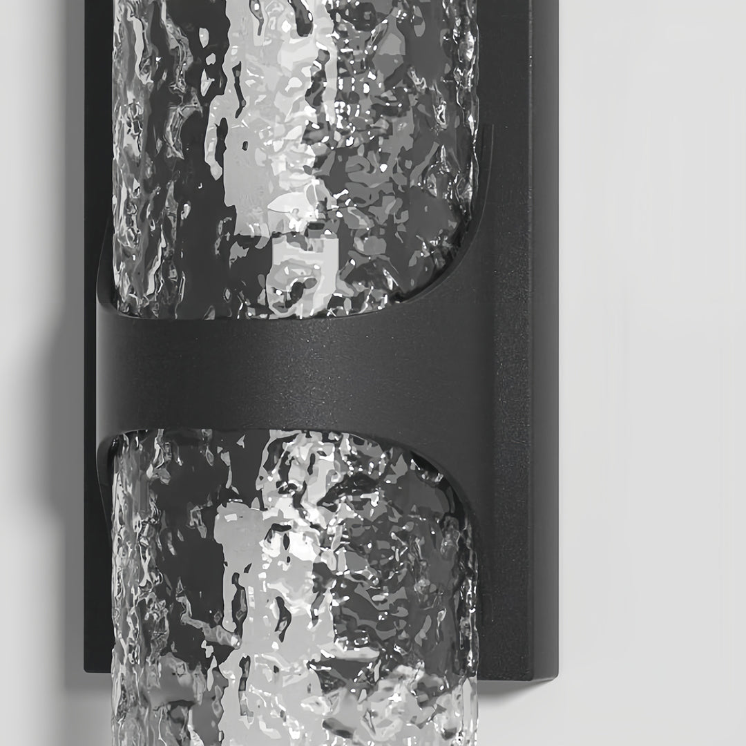 Detailed close-up of the textured black metal bracket and unlit ice glass shade on the contemporary black outdoor wall lights.