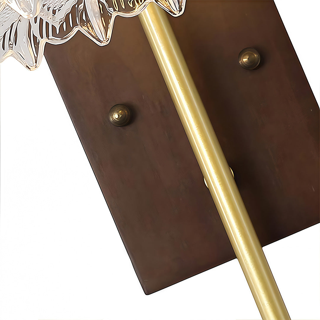 Detailed view of the dark wooden backplate and the adjustable brass arm of the glass wall lights fixture.