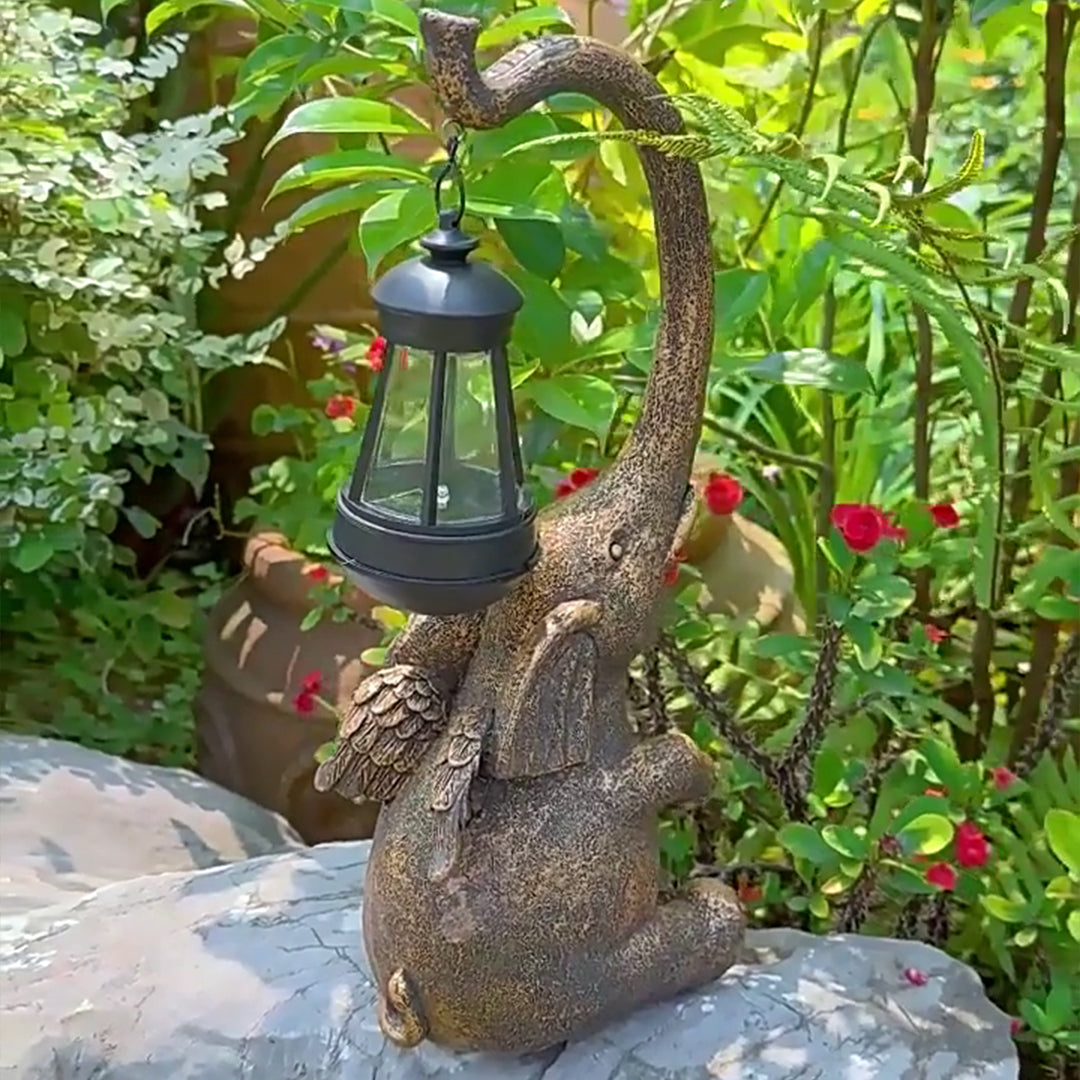 Detailed elephant garden statue with lantern positioned among red flowers and green foliage