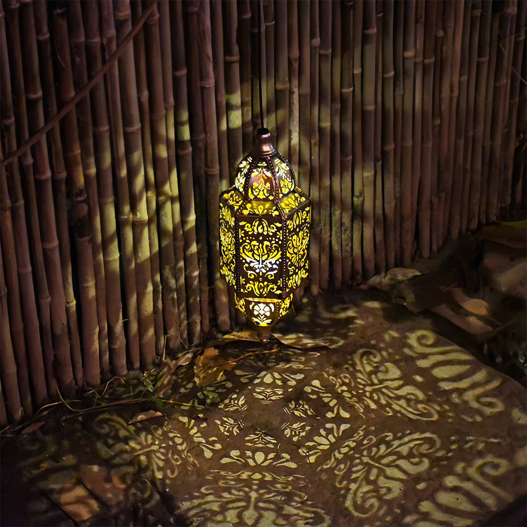 Detailed laser-cut outdoor moroccan lanterns creating bold, exotic shadows against a bamboo fence.
