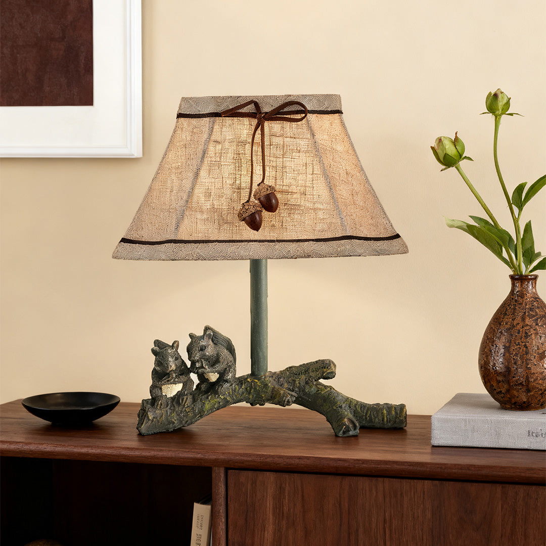 Detailed squirrel table lamp base molded from resin, featuring two squirrels perched on a log, placed on a dark wood dresser.