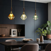 Diamond-shaped pendant lights over modern dining table with navy walls and sophisticated interior design elements