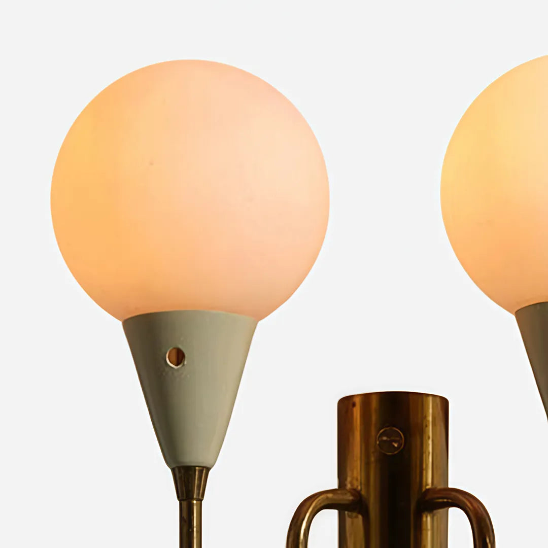 Double globe wall sconce close-up showing frosted globe shades and a brass wall mount.
