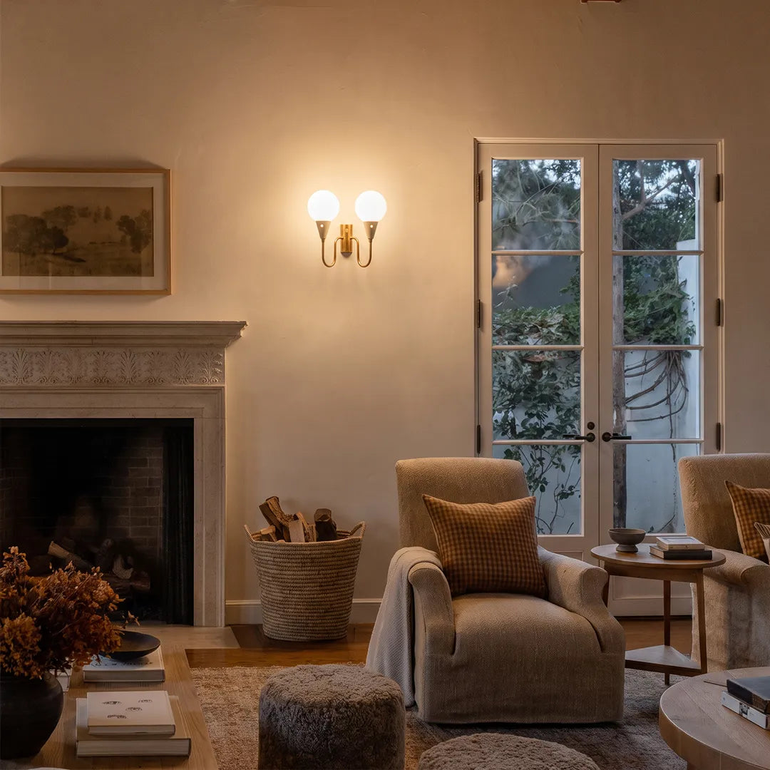 Double globe wall sconce installed in a living room beside a fireplace with warm ambient light.