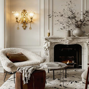 Double lamp wall lights with a classic gold finish, illuminating an elegant living room with a fireplace.
