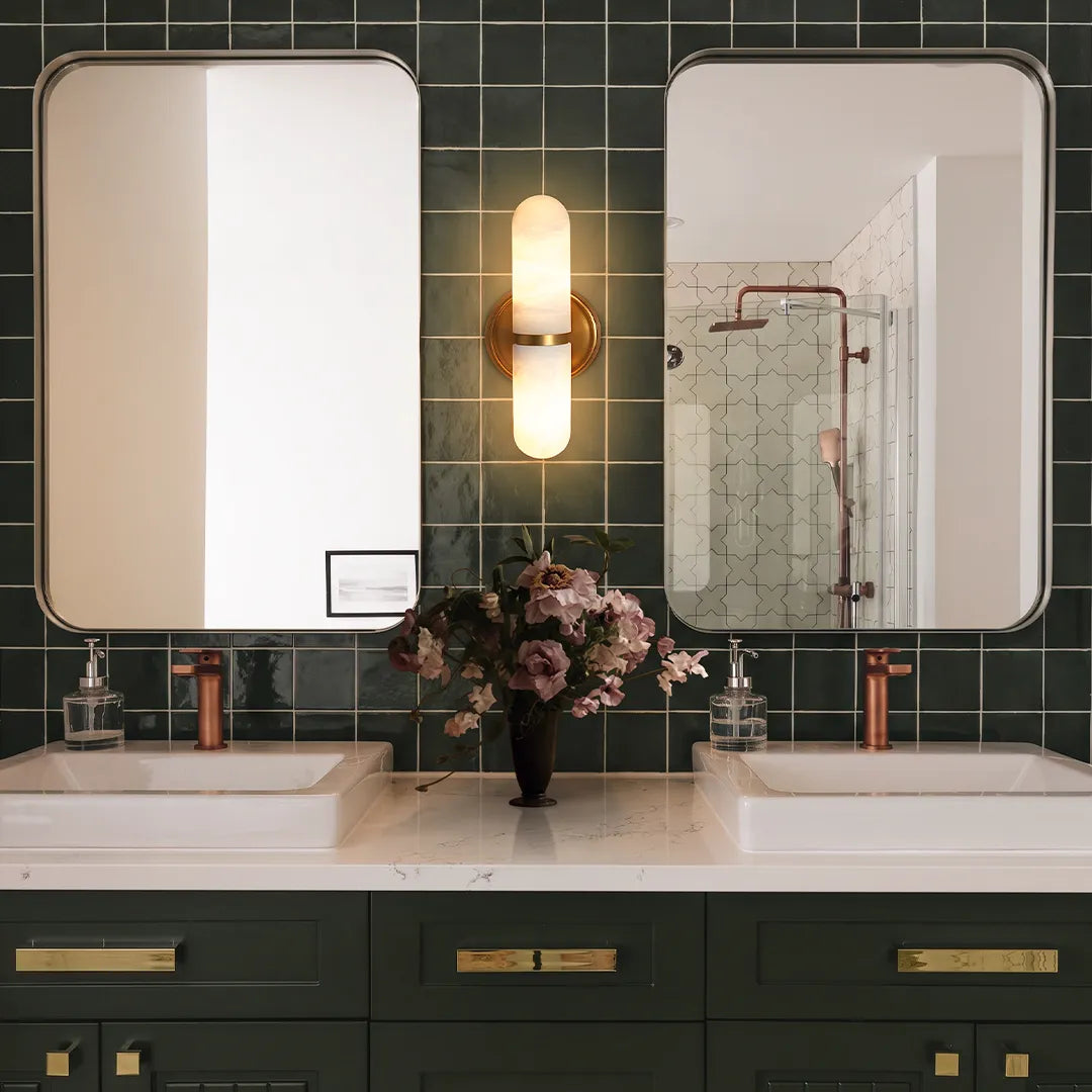 Double light wall sconce featured in a modern bathroom with dual mirrors and tiled walls.
