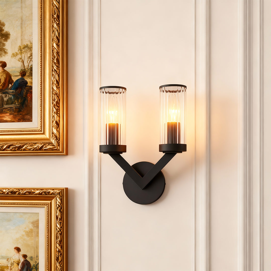 Double sconce wall light providing elegant lighting beside ornate gold-framed mirror