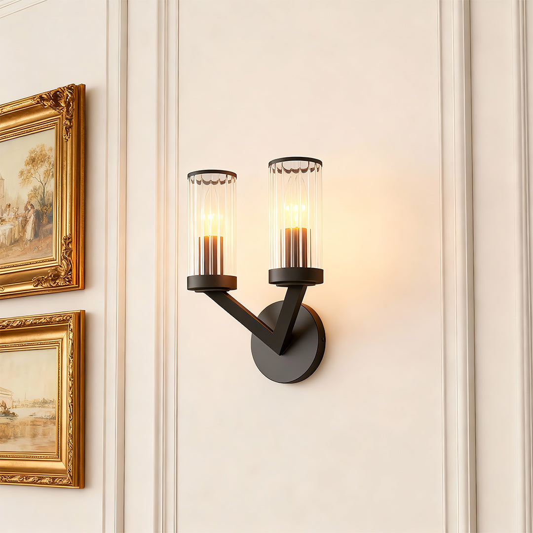 Double sconce wall light illuminating elegant hallway with ornate gold-framed mirror