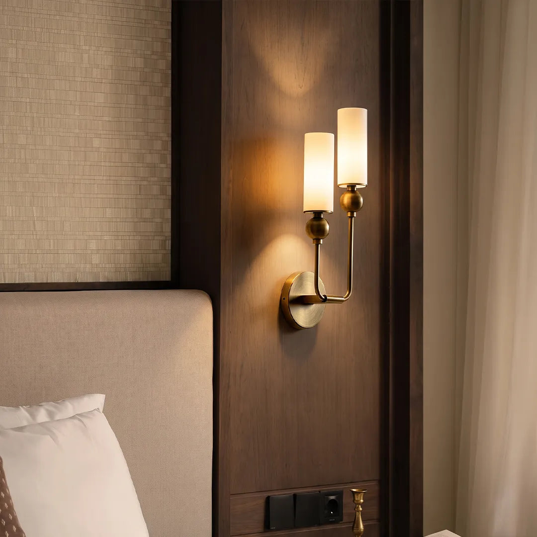 Double sconce wall light mounted on a wood accent wall beside a bed with elegant vertical arms.