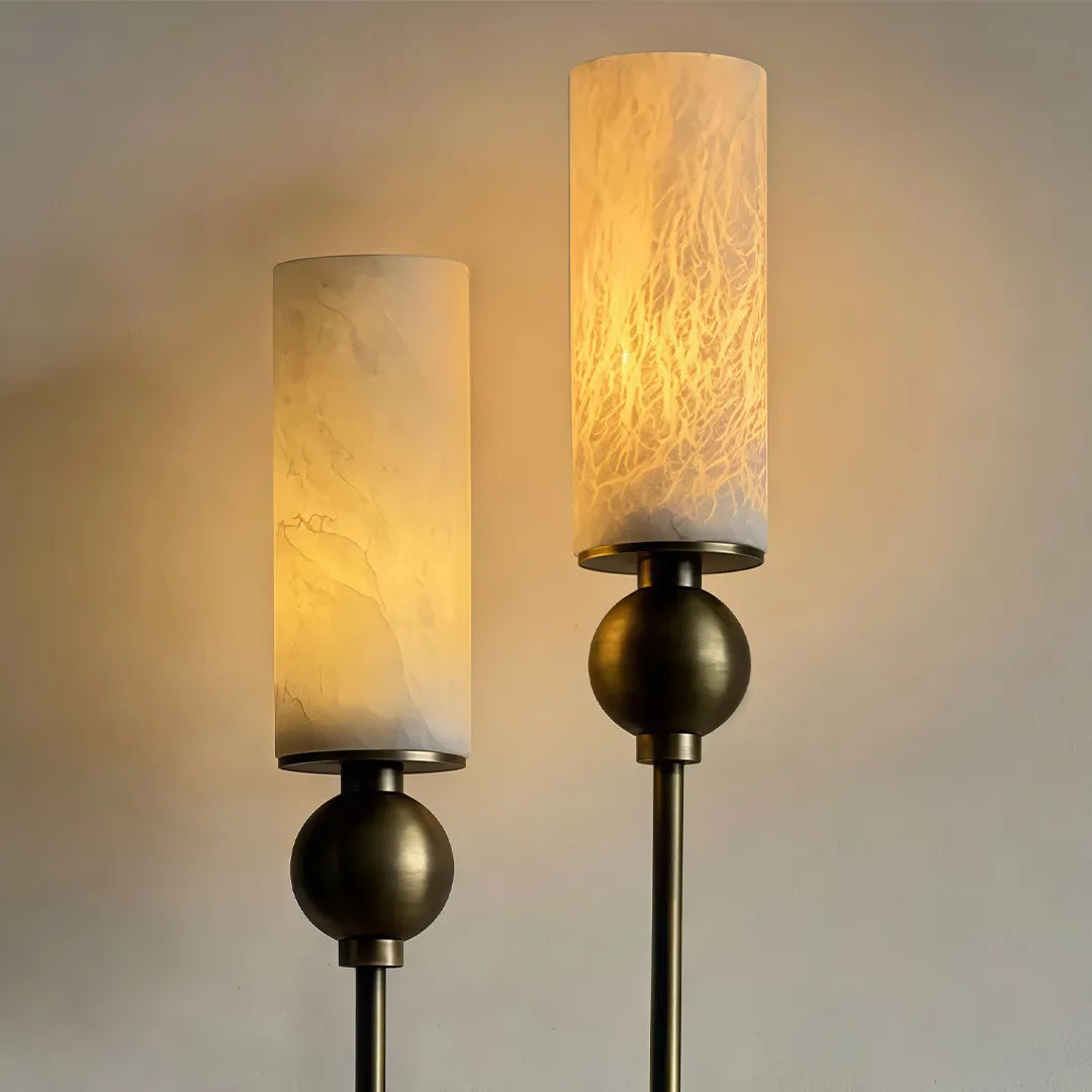 Double sconce wall light close-up showing two marble-look glass shades and a warm brass finish.