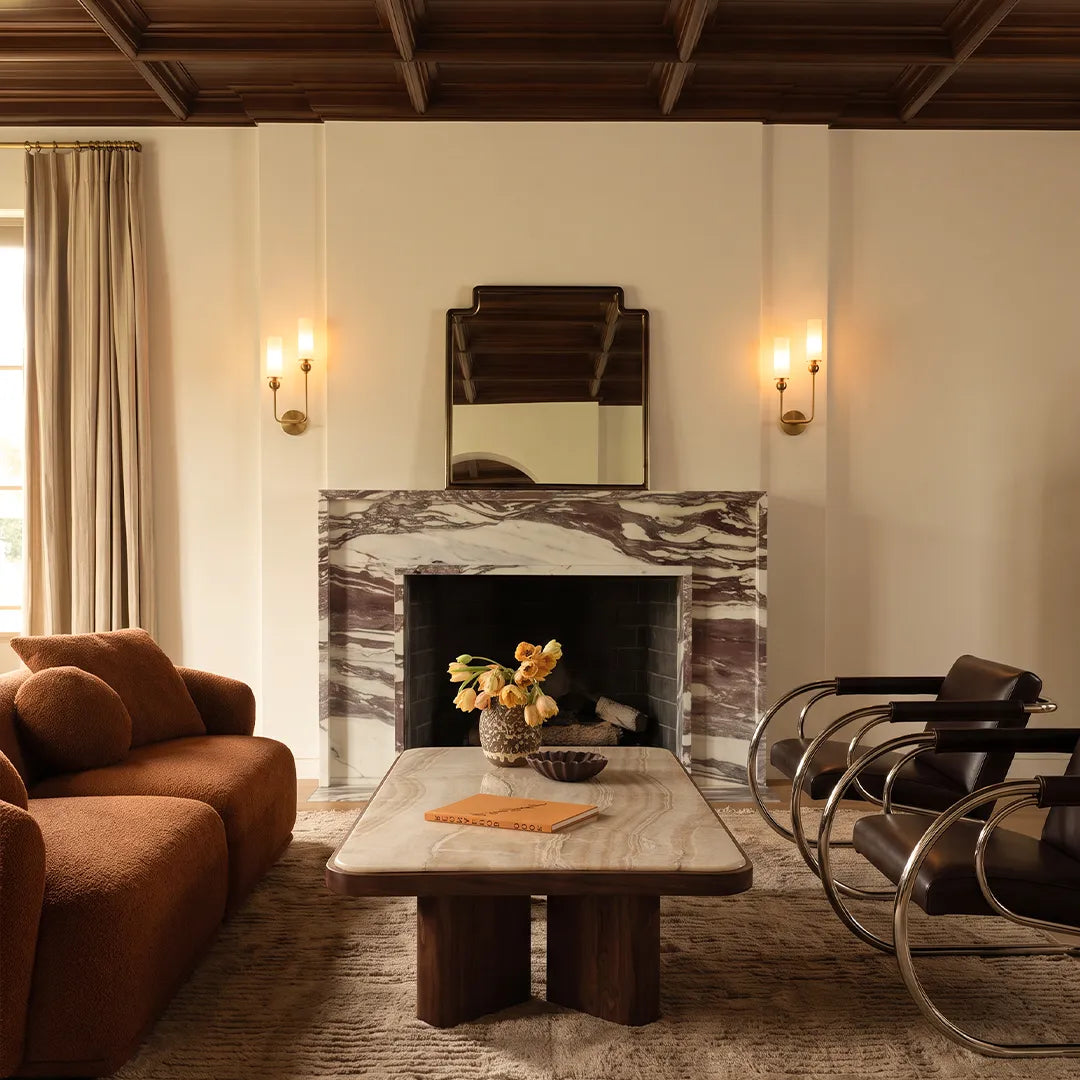 Double sconce wall light installed on a living room wall above a fireplace with soft warm illumination.