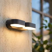 Double wall lights mounted on a textured exterior wall, featuring two rotatable heads with warm downward illumination.